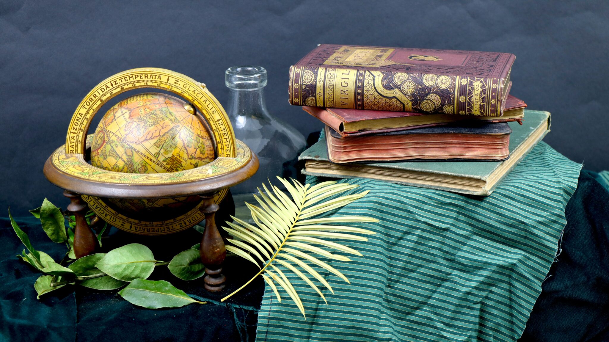 Still life of a gilt 18th century edition of Virgil's Aeneid with an antique globe.