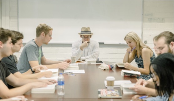 Dr. Honeycutt in class with students around a table.