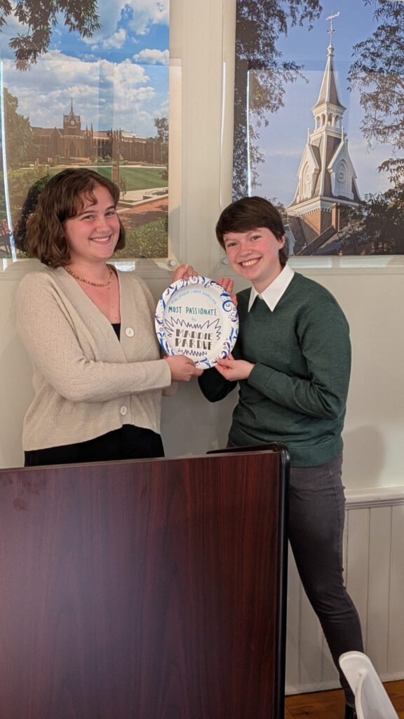 Two students stand behind a podium with a paper plate.