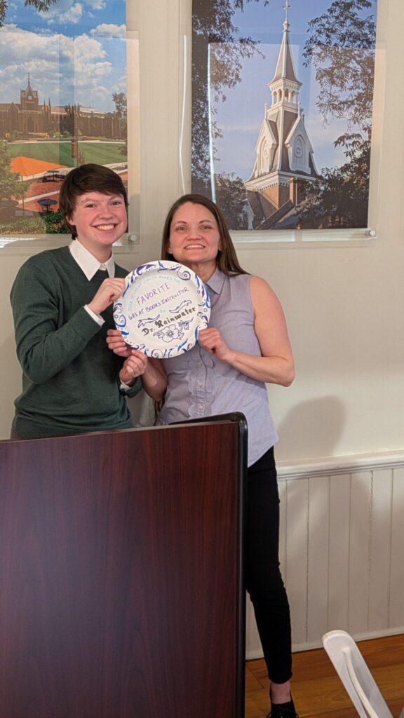 Two people stand behind a podium with a paper plate as an award.